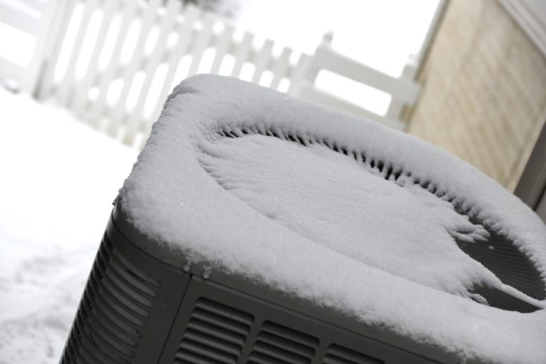 An air conditioning unit covered in snow, Should Air Conditioners Be Covered In The Winter?