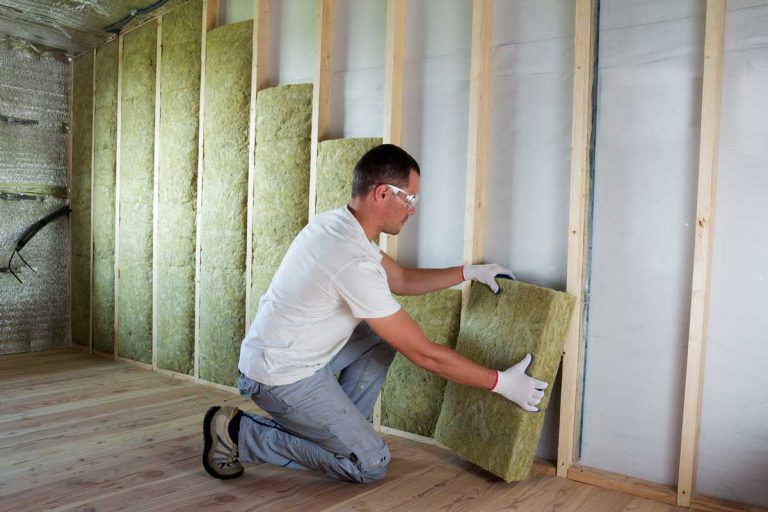 Worker in protective goggles and respirator insulating rock wool insulation in wooden frame for future house attic walls for cold barrier, How Much Does It Cost To Insulate A 1200 Sq Ft Attic?