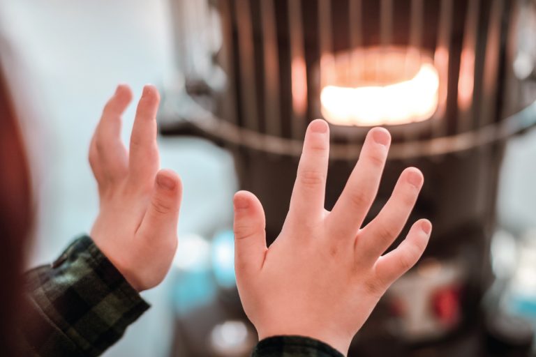 a boy warming his hands by the heater, types of space heaters for homes
