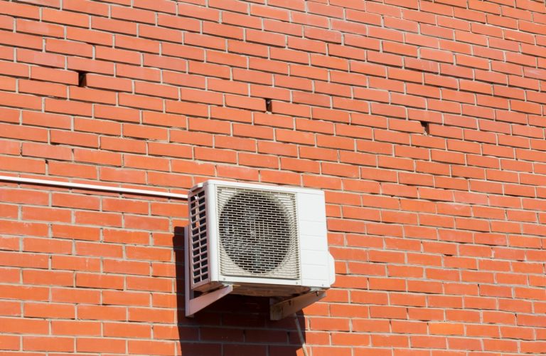 air conditioning unit installed outside on a brick wall