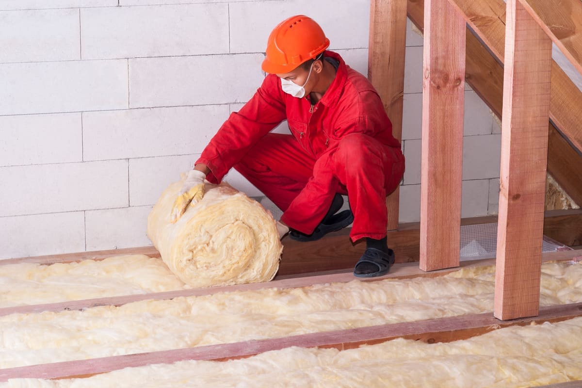 A man rolling mineral rockwool insulation on the attic, Can You Put New Attic Insulation Over Old?