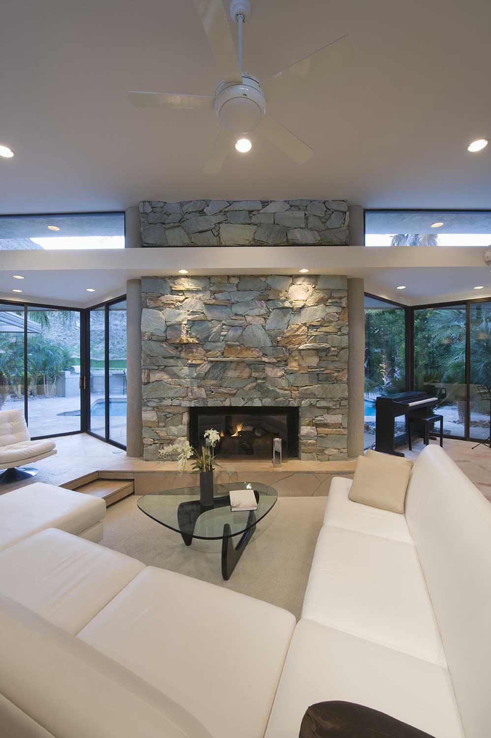 Seating area with white corner sofa, glass table and fireplace
