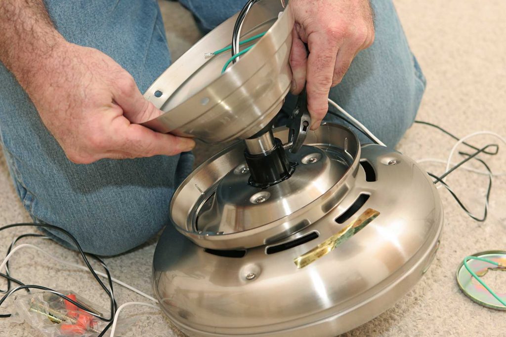 An electrician assembling a ceiling fan motor