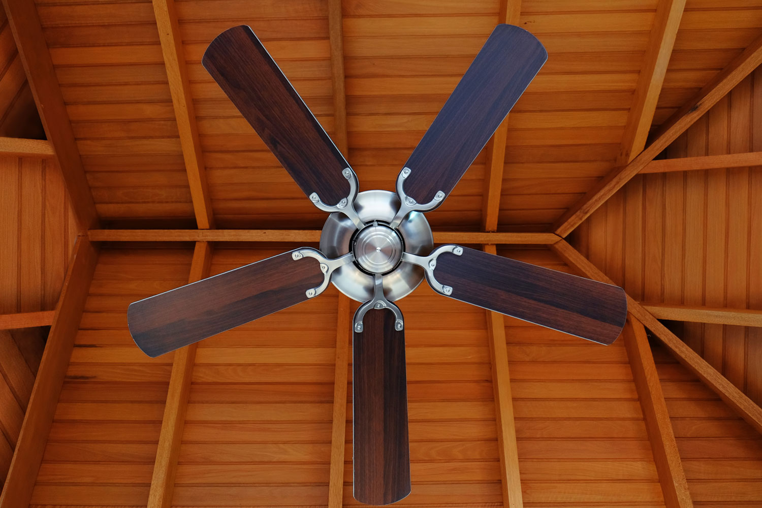 A modern wooden blade ceiling fan inside a rustic living room