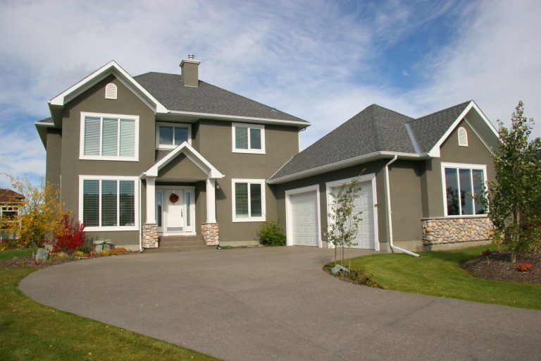 Exterior of a modern gray stucco walled home with white painted window trims and a huge driveway, Does Stucco Have An R-Value?