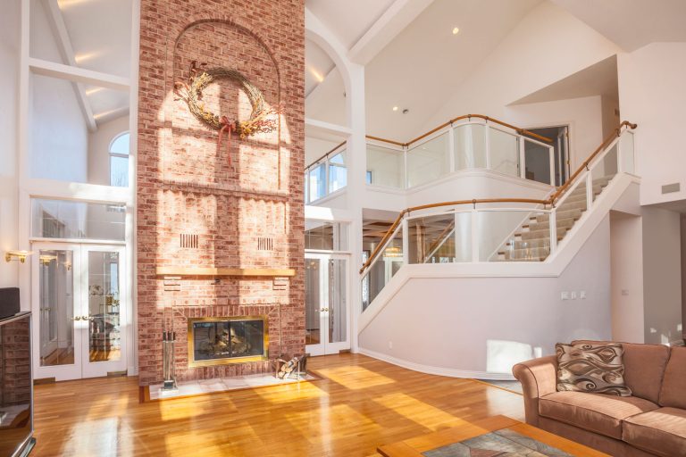 A huge contemporary living room with a cathedral ceiling brickstone fireplace, and a polished wooden flooring, Do Cathedral Ceilings Need Ventilation?