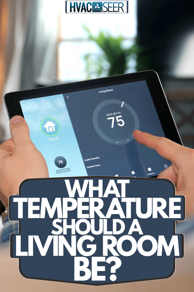 A man adjusting the thermostat of the living room in his Ipad, What Temperature Should A Living Room Be?