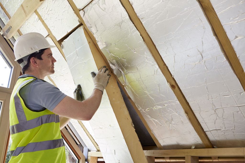 A man fitting insulation on the ceiling