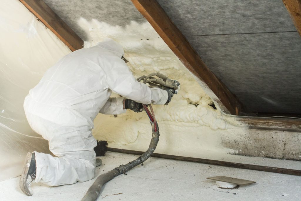 An insulation sprayer applying insulation foam on the attic ceiling