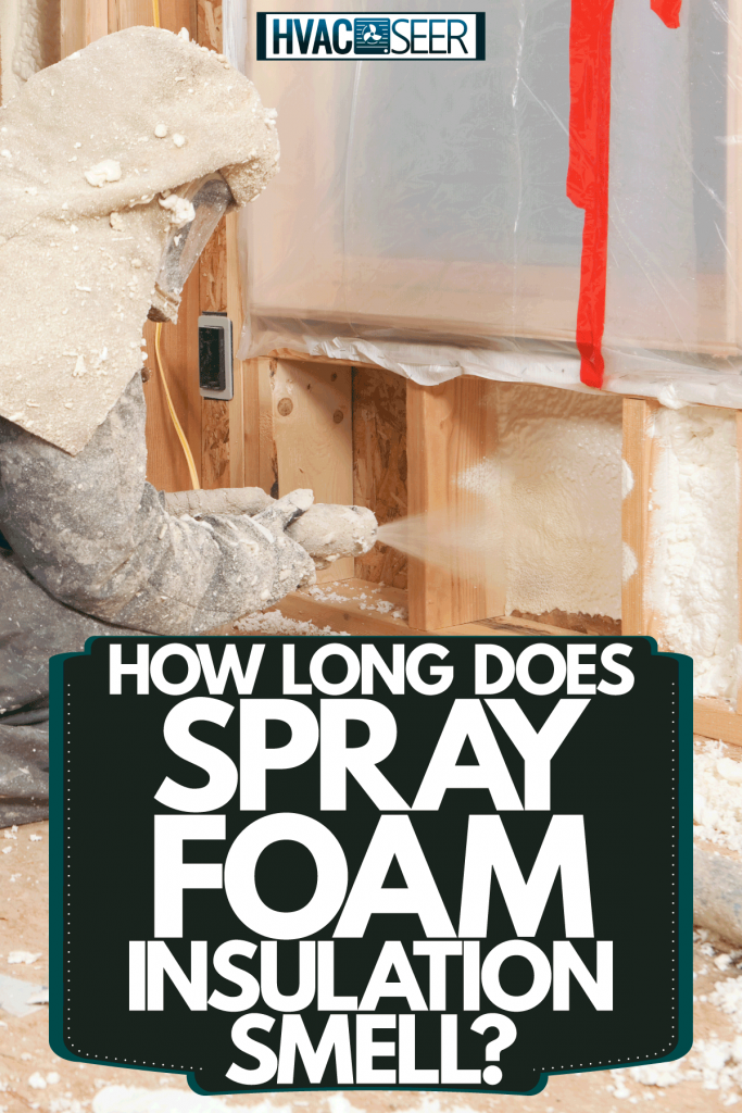 A worker spraying foam insulation on the wall of a house under construction, How Long Does Spray Foam Insulation Smell?