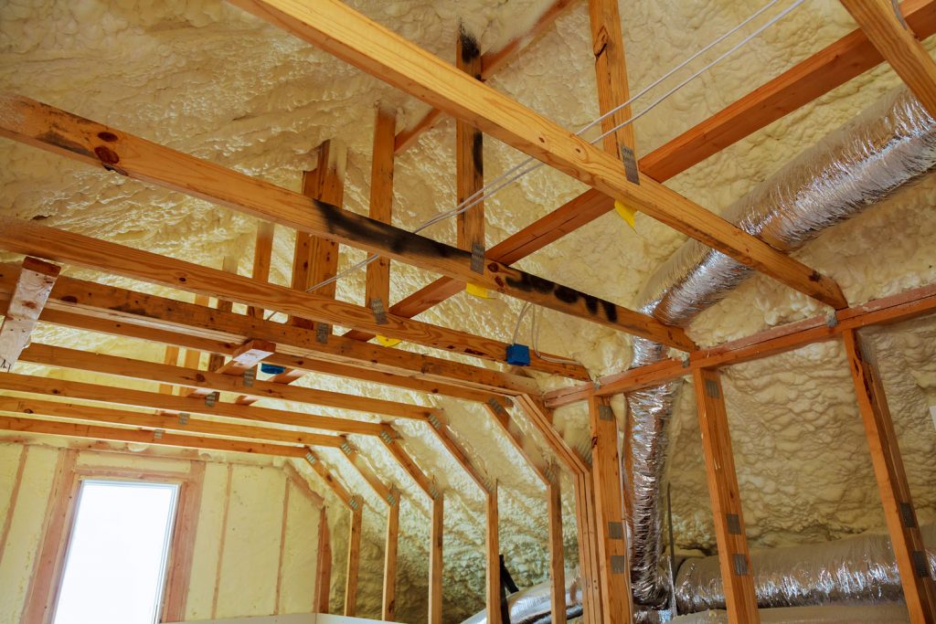 Inner view of an attic of a house with spray foam insulation on the ceiling and walls with burn marks