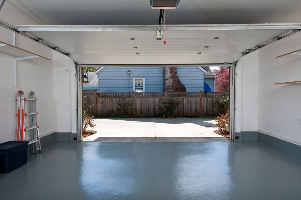 Interior of a white and empty garage with the garage door pulled open