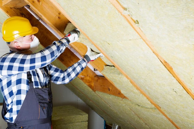 Man installing thermal insulation layer, How To Insulate A Sloped Ceiling [A Complete Guide]