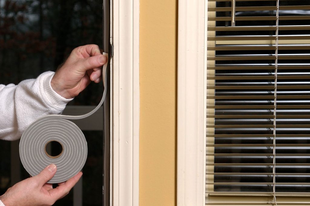 A man installing weather stripping on the front door