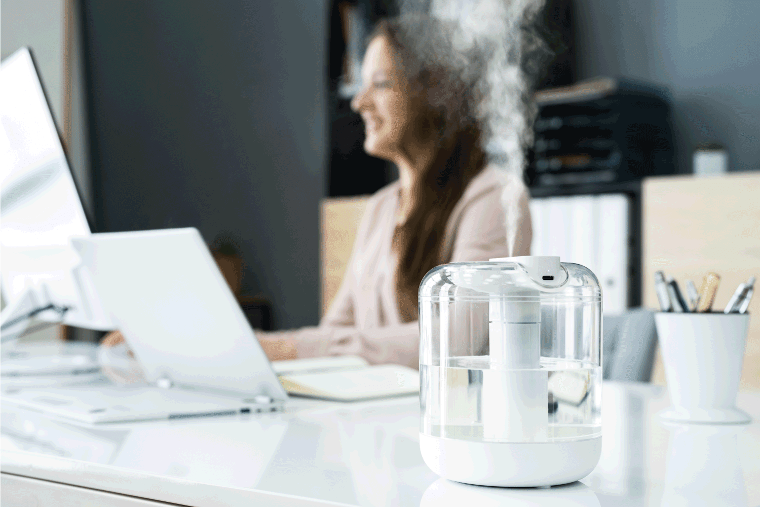 Air Humidifier Device At Office Desk Near Woman Working