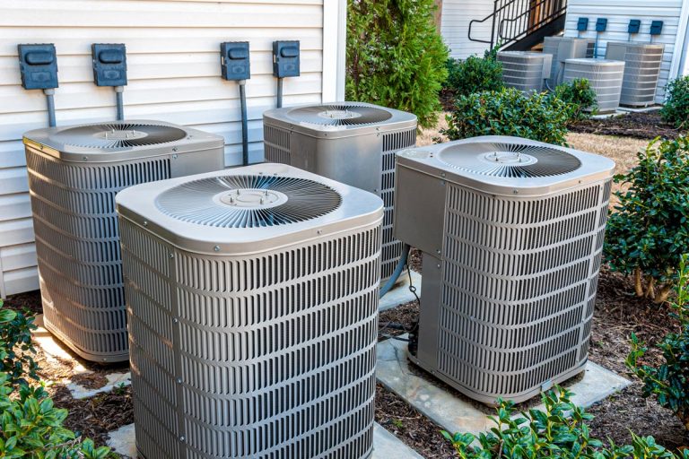 Horizontal shot of four air conditioning units outside of an upscale apartment complex, How Long Should A Central AC Run At A Time?