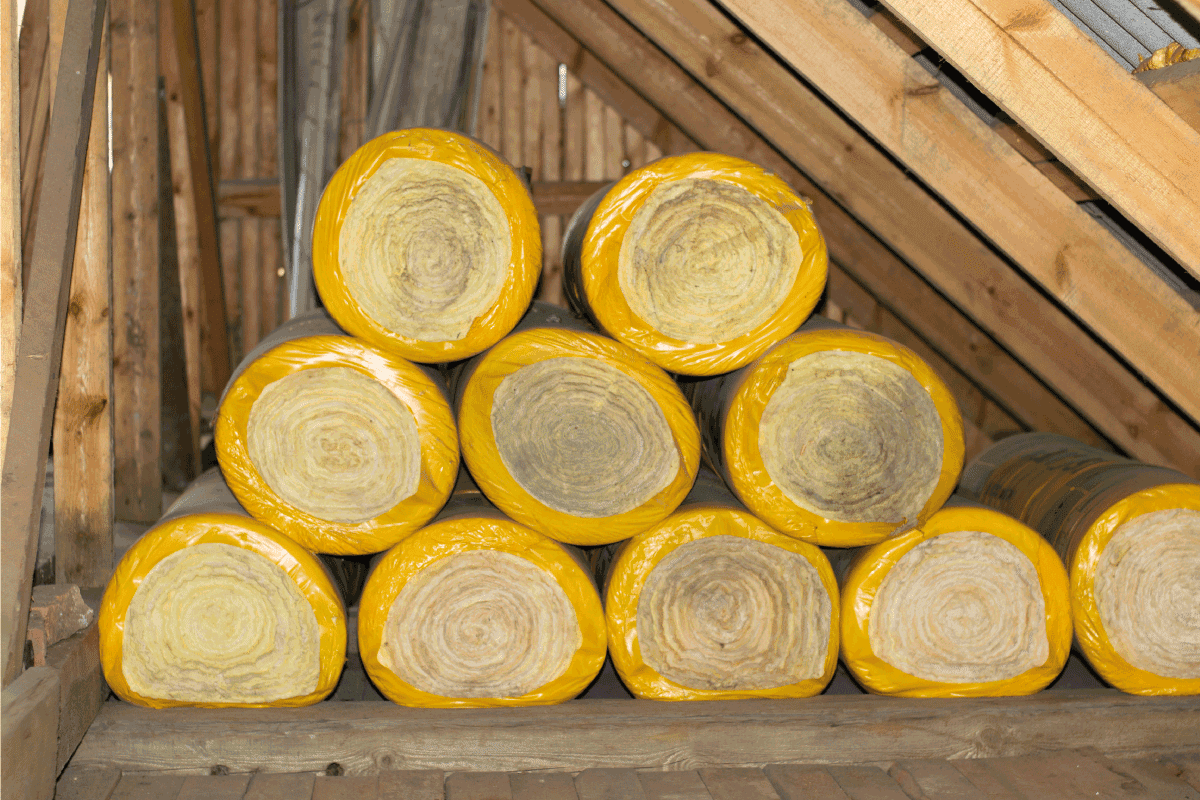 Insulation rolls in yellow packaging in the attic of a wooden house. ready to use. How Much Does It Cost To Insulate A 1,500 Square Foot House