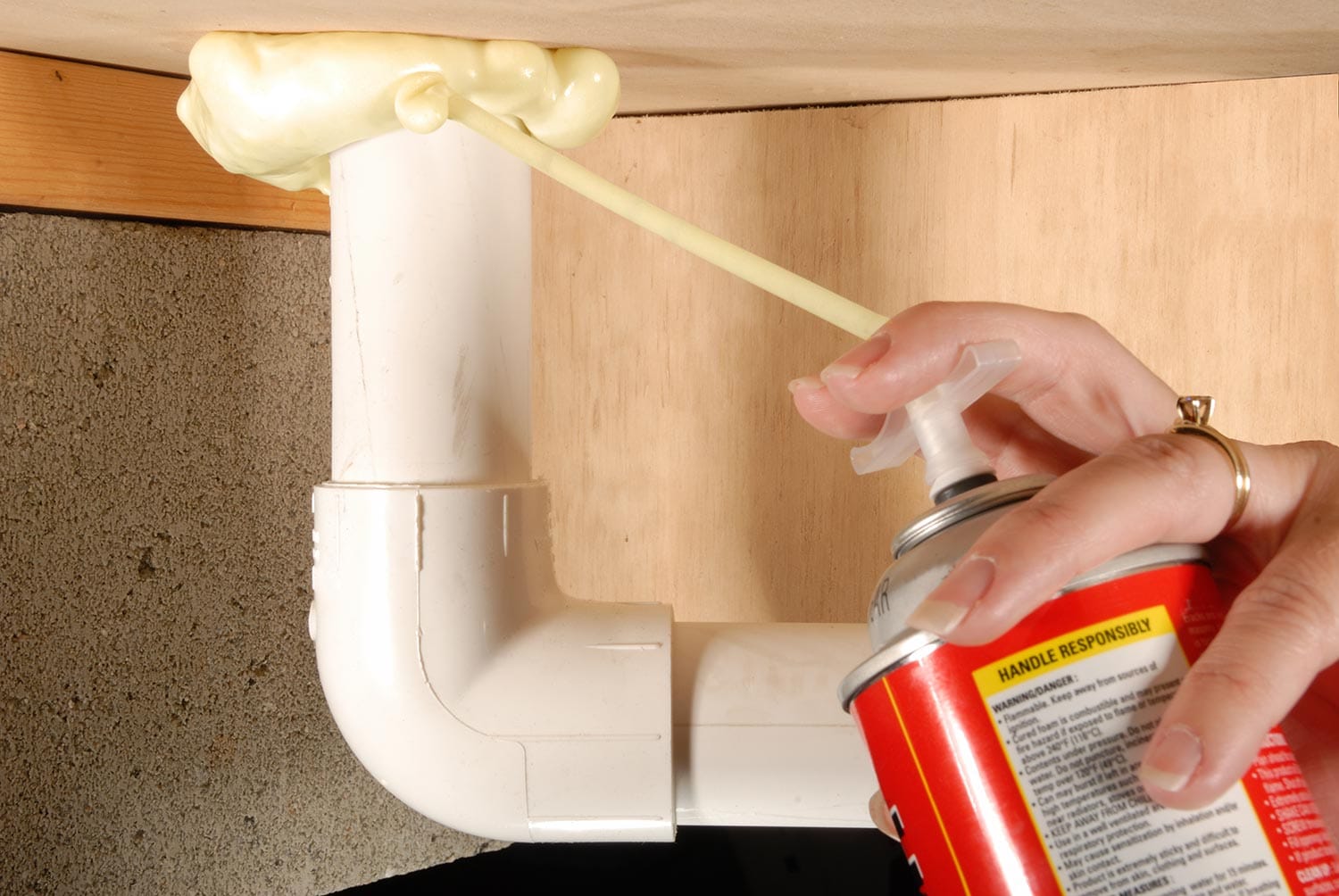 Sealing the air leaks around plumbing penetrations underneath a home with an insulating expandable foam sealant.
