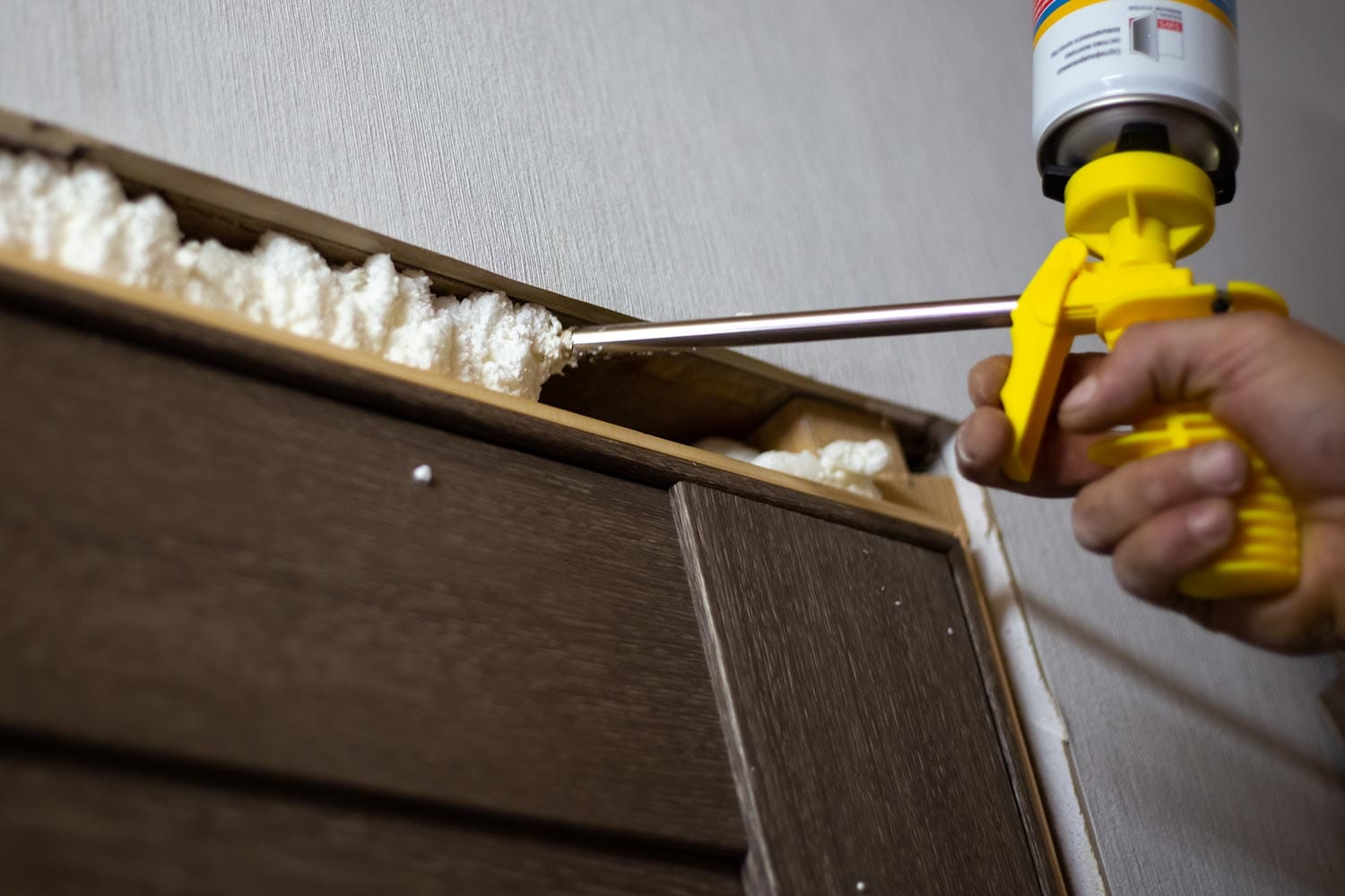 The master foams up the gaps between the door and the wall with polyurethane foam