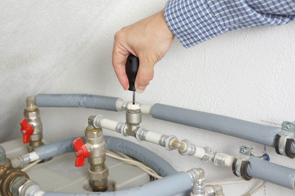 A man adjusting the pipe fixture of the central heating system