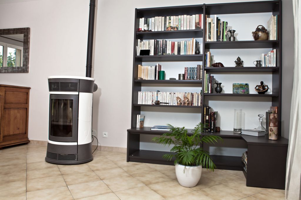 A white pellet stove placed next to the tall wooden divider in the living room