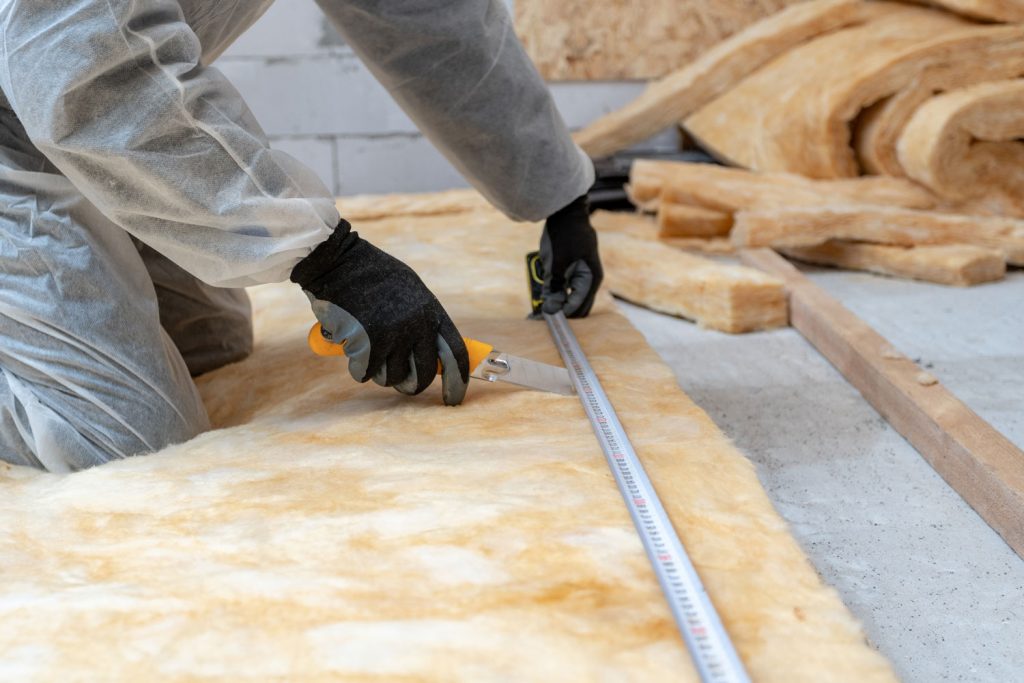 A worker installing thermal insulation on the roof attic