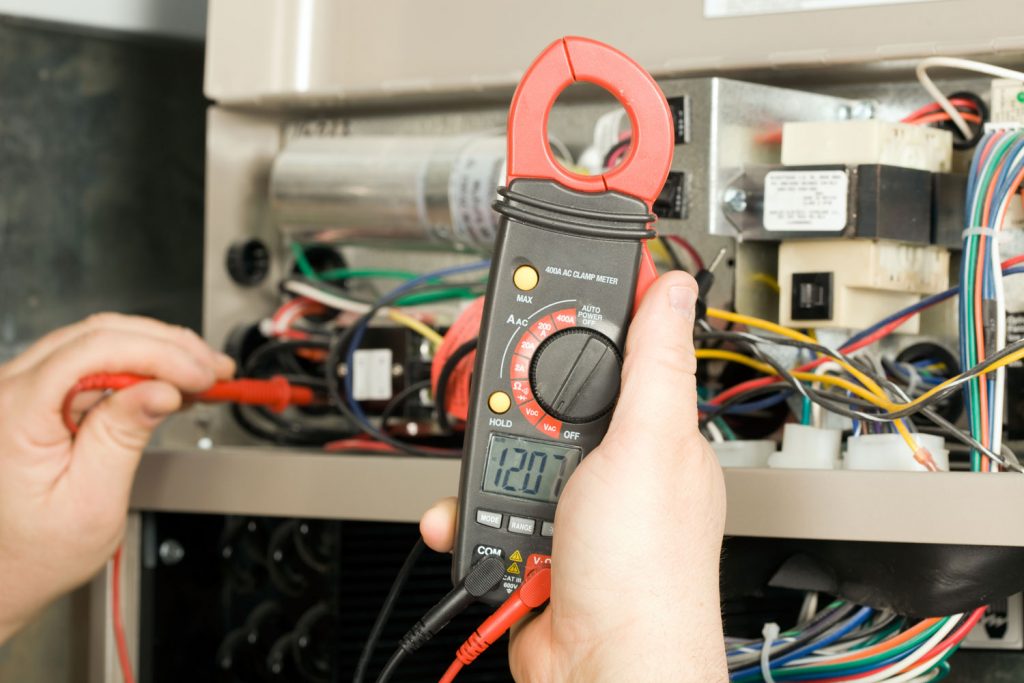 An electrician checking the voltage of the electric furnace