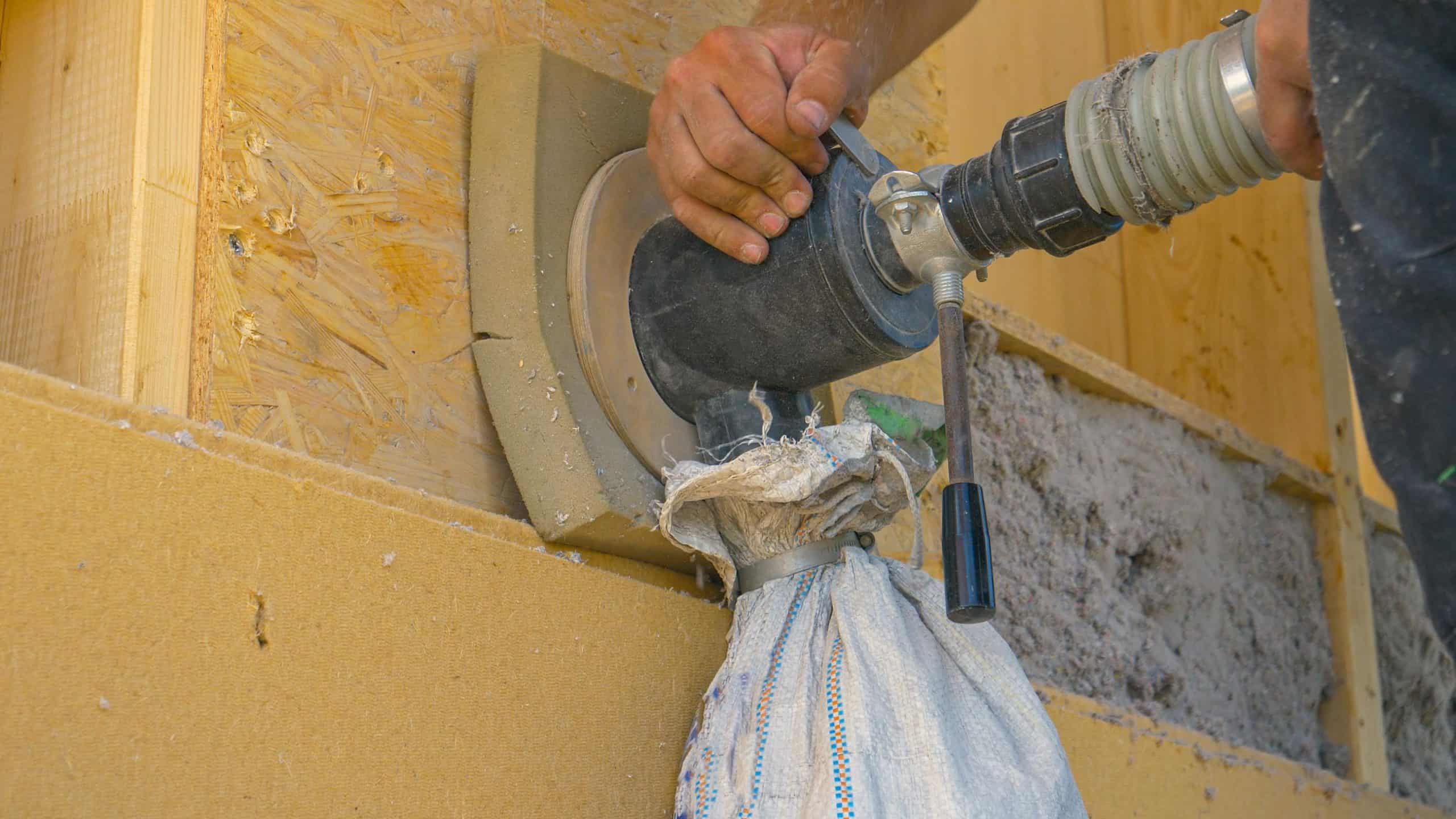 Builder uses a blower to insulate the wood wall with recycled paper