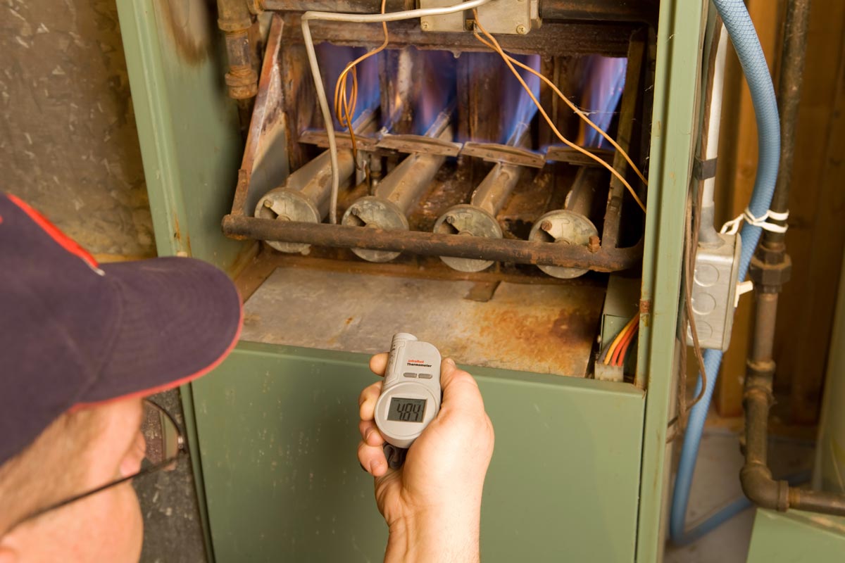 A repairman with digital infrared thermometer checks gas furnace output temperature, Is A Furnace Supposed To Make Noise?