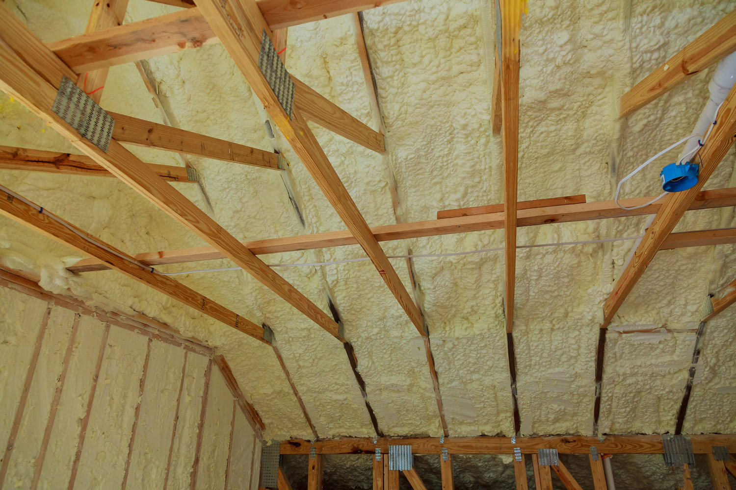 The ceiling of a house with spray foam insulation in between each trusses