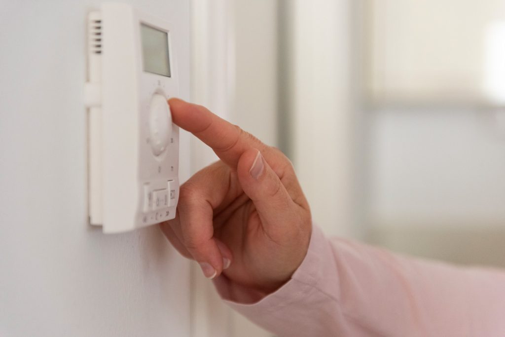 Women adjusting the temperature on home thermostat.