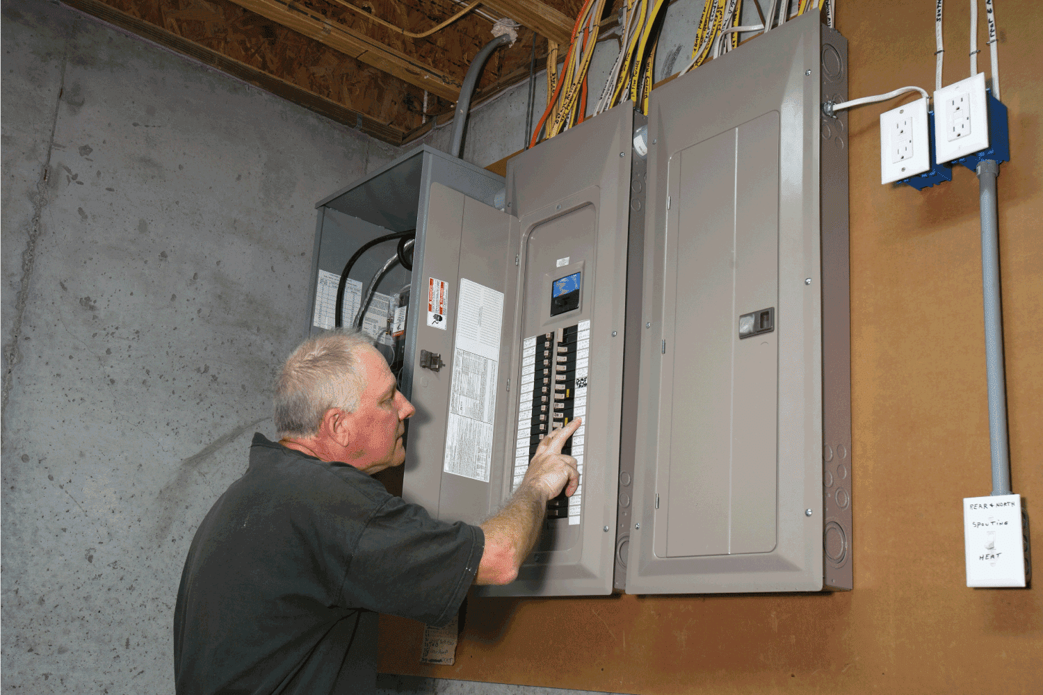 man checking the labels on his home fuse box