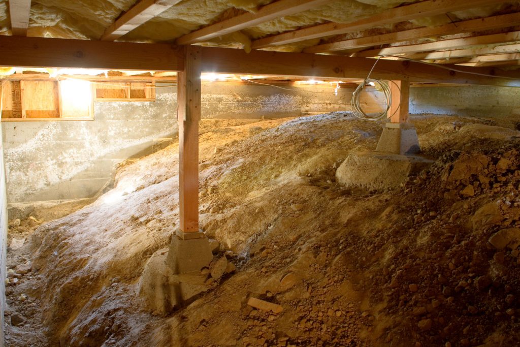  A crawl space under a house with visible insulation and wooden framing