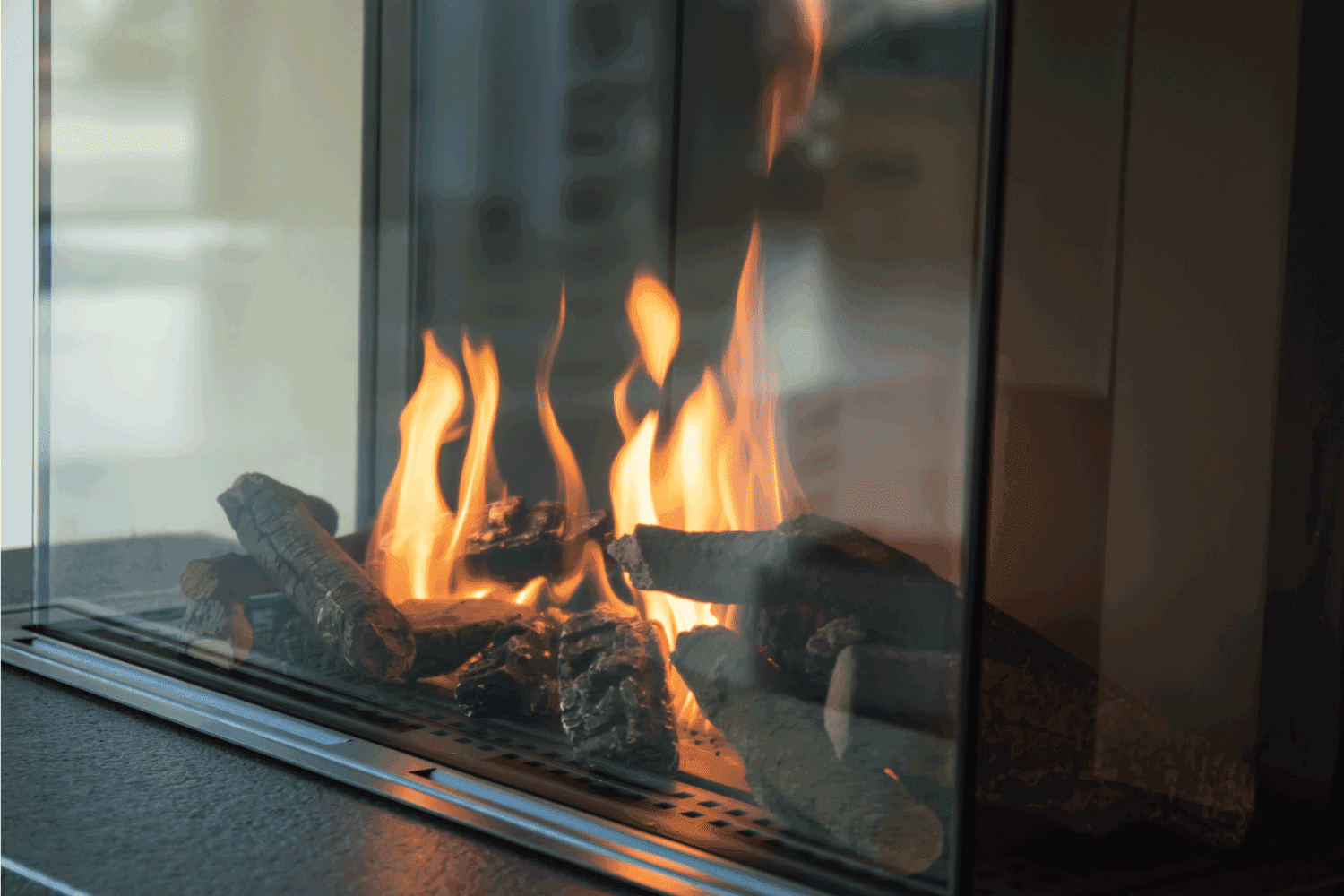 A fire burns in a glass fireplace, radiates heat