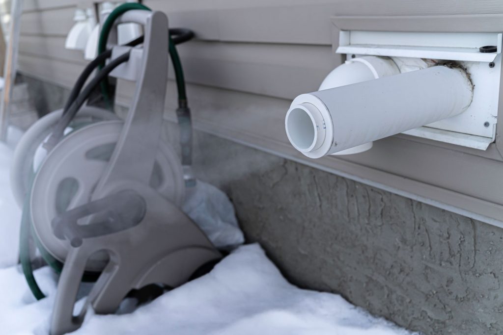 A furnace exhaust vent pipe blowing steam to the cold winter air