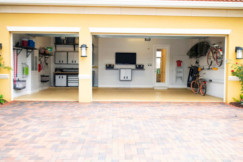 A gorgeous tiled garage painted in yellow with white painted walls and cabinets with bicycles hanged on the wall
