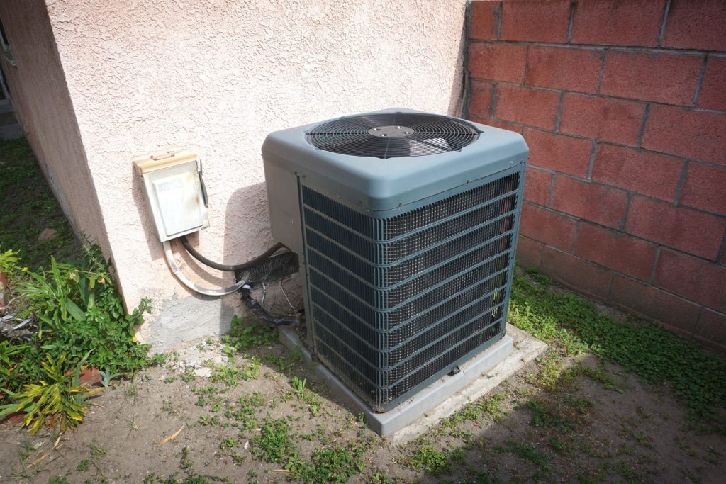 A gray colored air heat pump installed outside a house