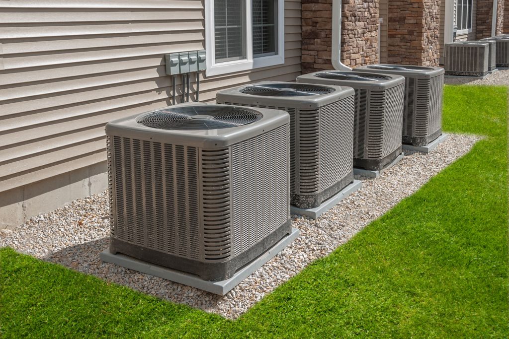 A gray colored heat pumps placed beside the house