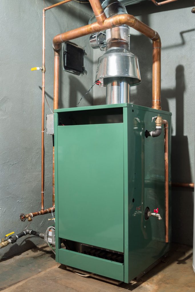 A green colored furnace photographed in the basement