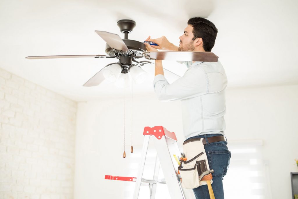 A home service repairman fixing the ceiling fan