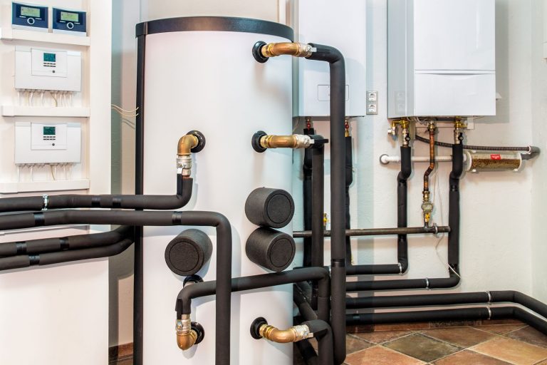 A huge white boiler with heavily insulated pipes and circuit breakers on the wall, How To Keep Furnace Or HVAC Condensate Line From Freezing, How To Keep Furnace Or HVAC Condensate Line From Freezing