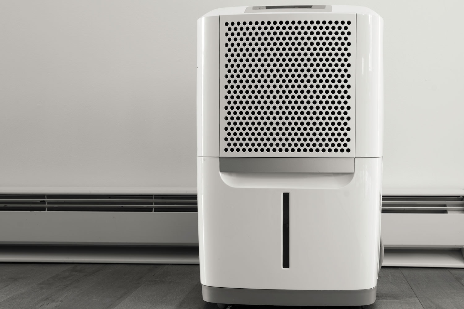 A white dehumidifier placed on the side of living room