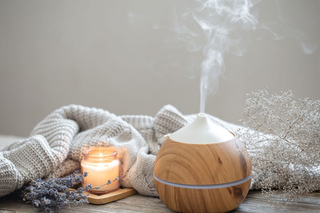 A wooden covered humidifier with a scented candle on the side