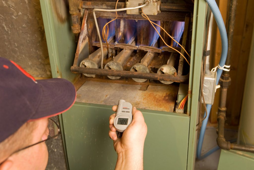 A worker checking the temperature of the furnace using digital thermometer