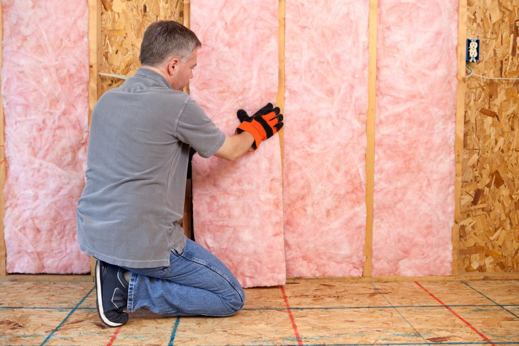 A worker placing a huge block of fiberglass insulation on the wall