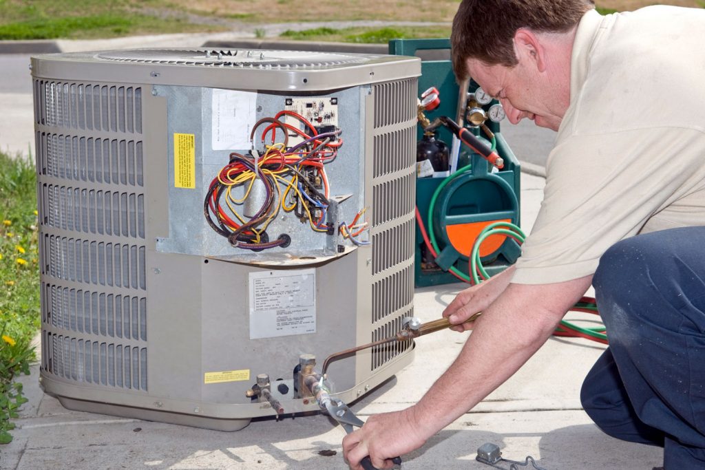 An air conditioning specialist fixing the power outlet of the AC condenser