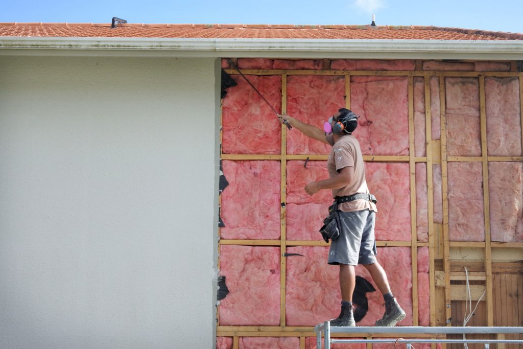 An insulation contractor removing old fiberglass insulation of a house