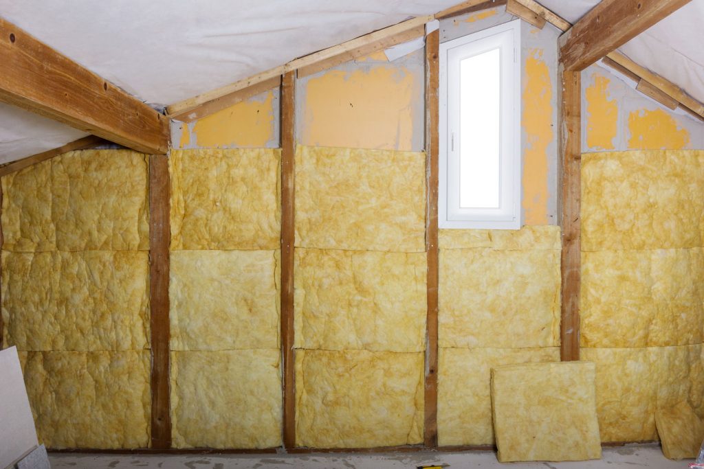 Blocks of mineral wool packed in the wooden membranes of the house attic