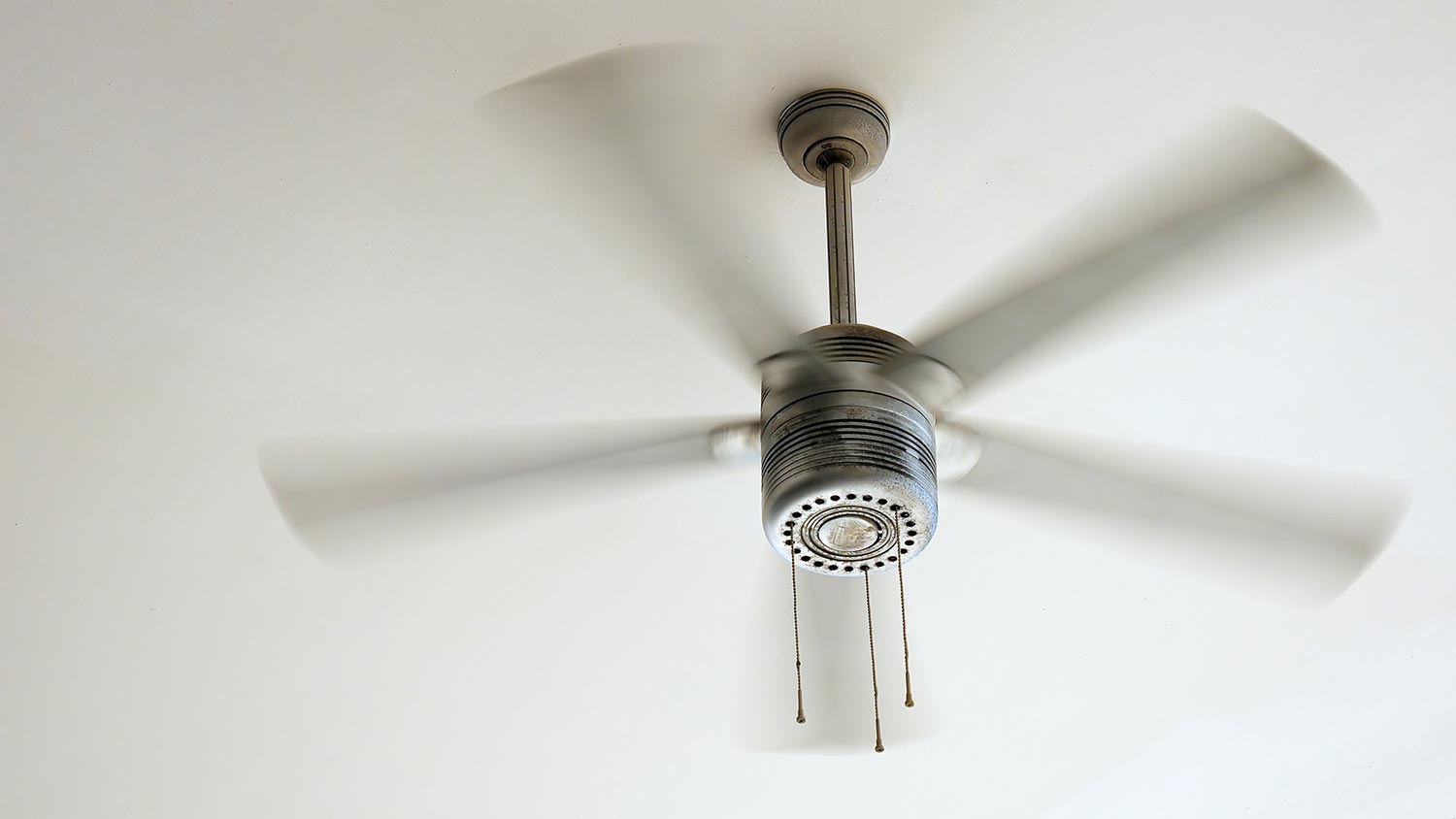 Ceiling fan is rotating at the ceiling of the room