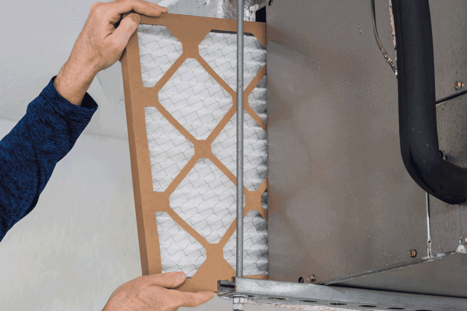 HVAC service technician changing dirty indoor air filter in residential heating and air conditioning system